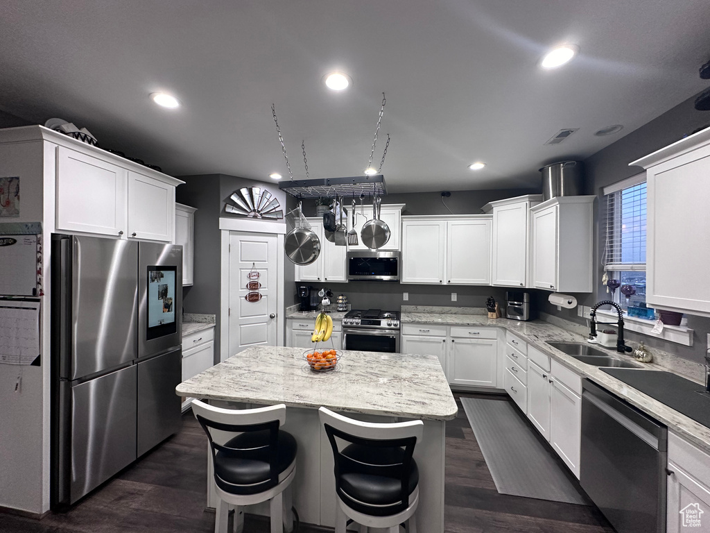 Kitchen with dark hardwood / wood-style floors, a kitchen island, stainless steel appliances, and white cabinetry