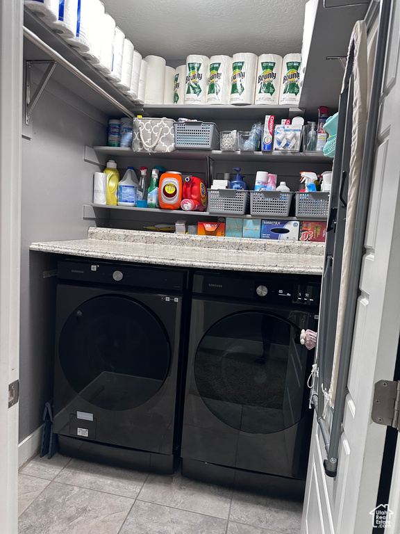 Laundry room with light tile floors and washing machine and clothes dryer