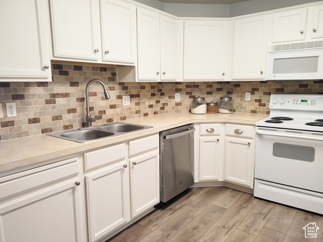 Kitchen featuring white cabinetry, white appliances, light hardwood / wood-style floors, and sink