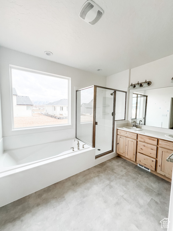 Bathroom with separate shower and tub, a wealth of natural light, and double sink vanity