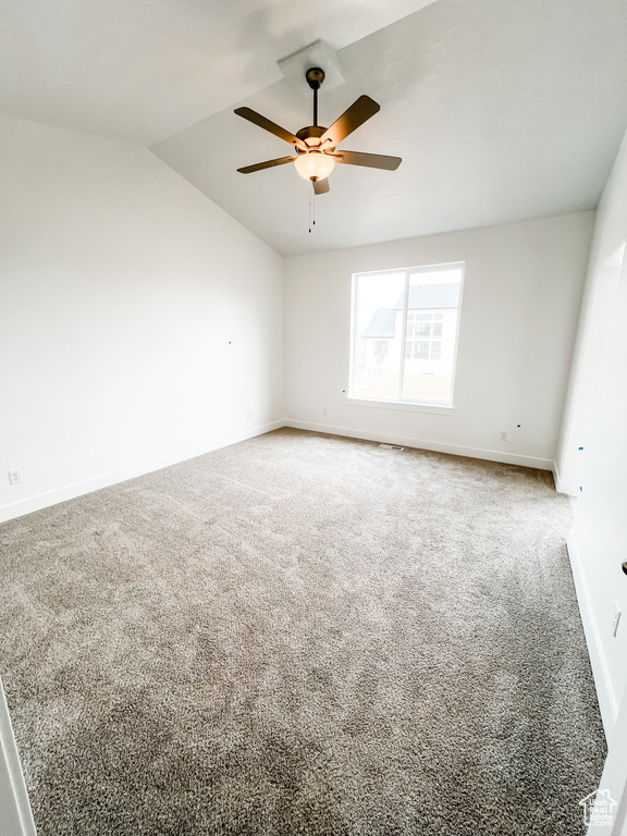 Spare room with ceiling fan, lofted ceiling, and carpet flooring