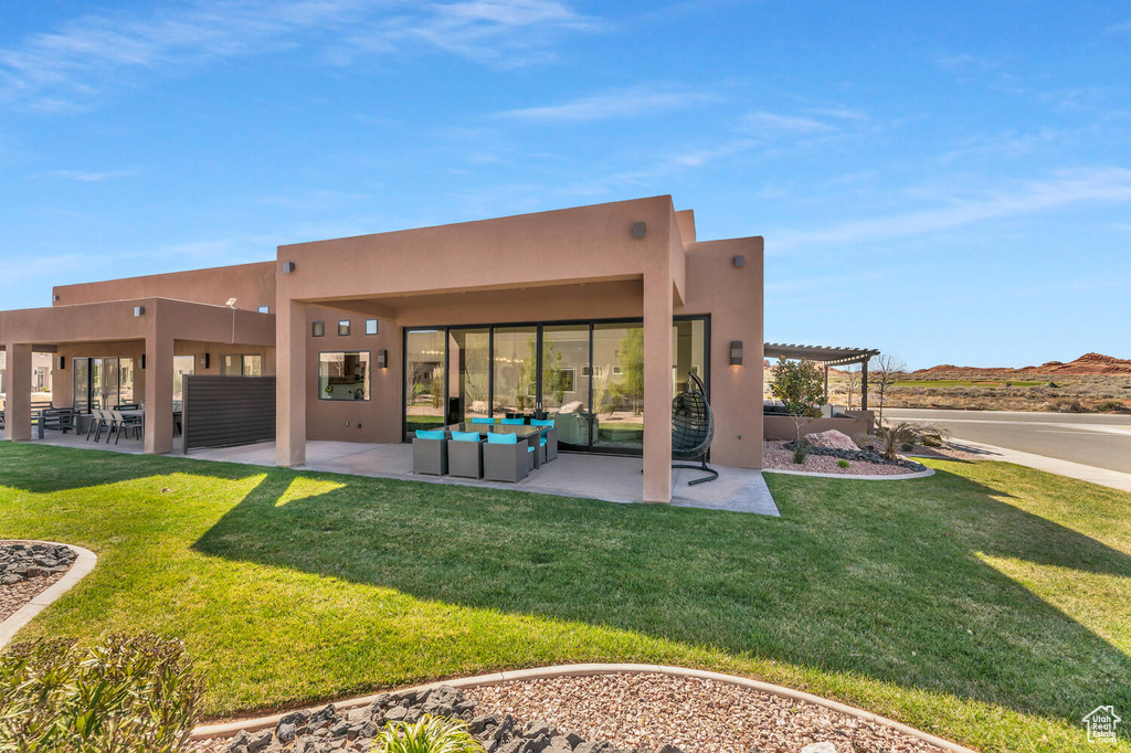 Back of property featuring a lawn, a patio area, a pergola, and an outdoor hangout area