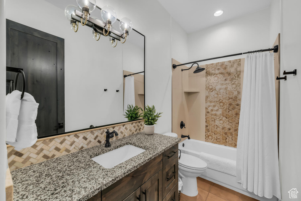 Full bathroom with vanity, shower / bath combo, toilet, tile floors, and backsplash