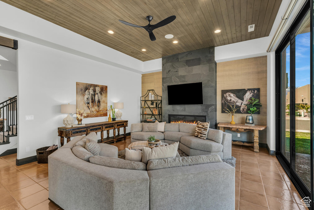 Tiled living room with ceiling fan, a fireplace, and wooden ceiling