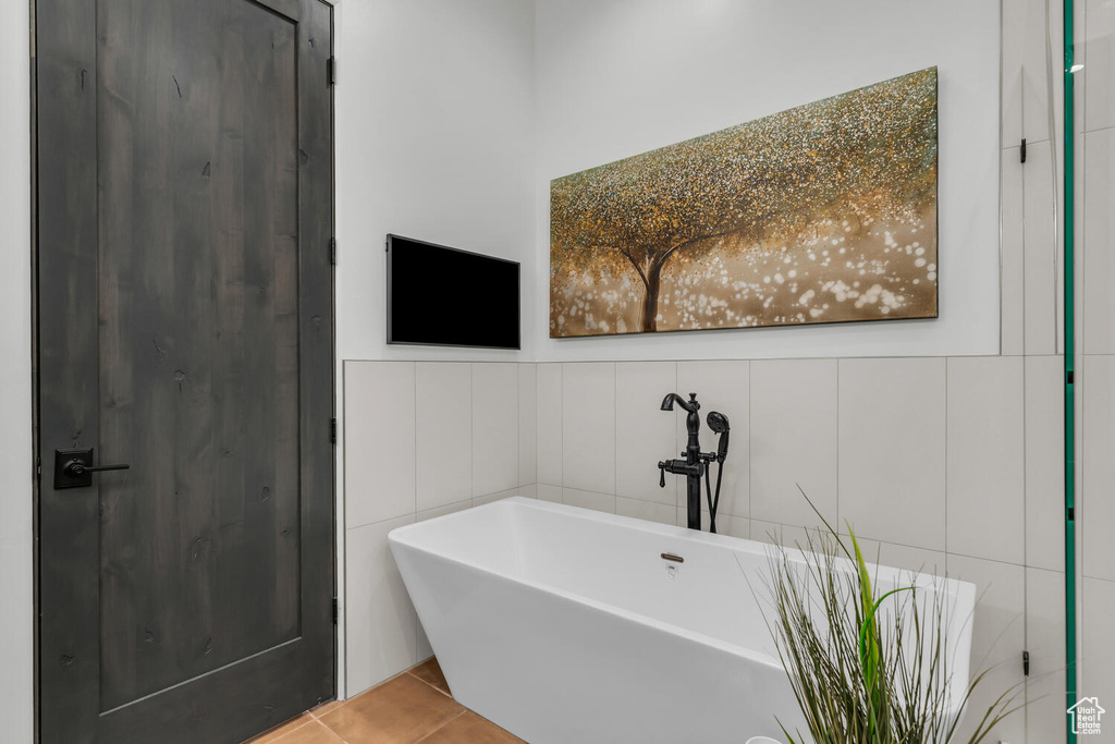 Bathroom featuring a bathtub, tile walls, and tile floors