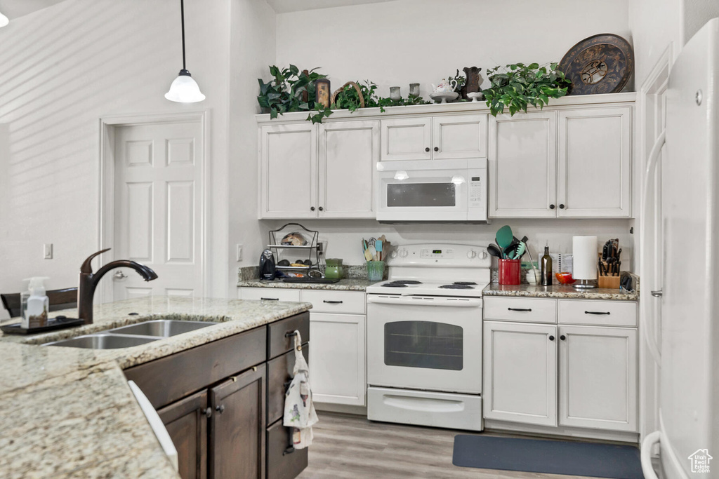 Kitchen featuring white cabinets, white appliances, sink, light wood-type flooring, and decorative light fixtures