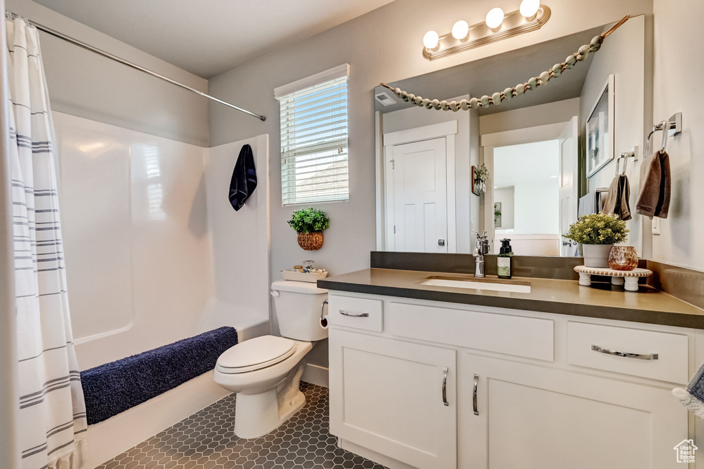 Full bathroom with tile floors, large vanity, toilet, and shower / bath combination with curtain