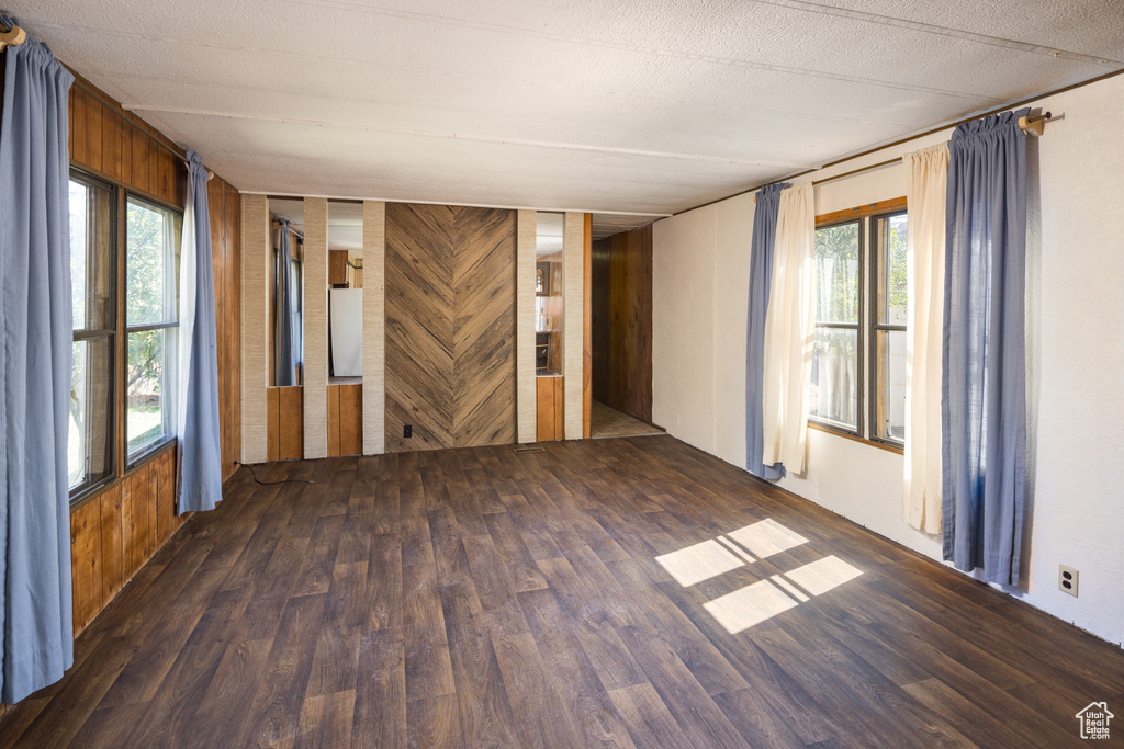 Spare room featuring wood walls, dark hardwood / wood-style floors, and a textured ceiling