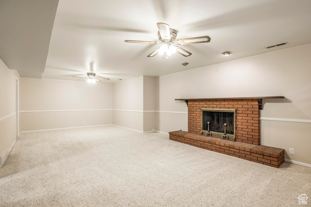 Unfurnished living room with a brick fireplace, light carpet, and ceiling fan