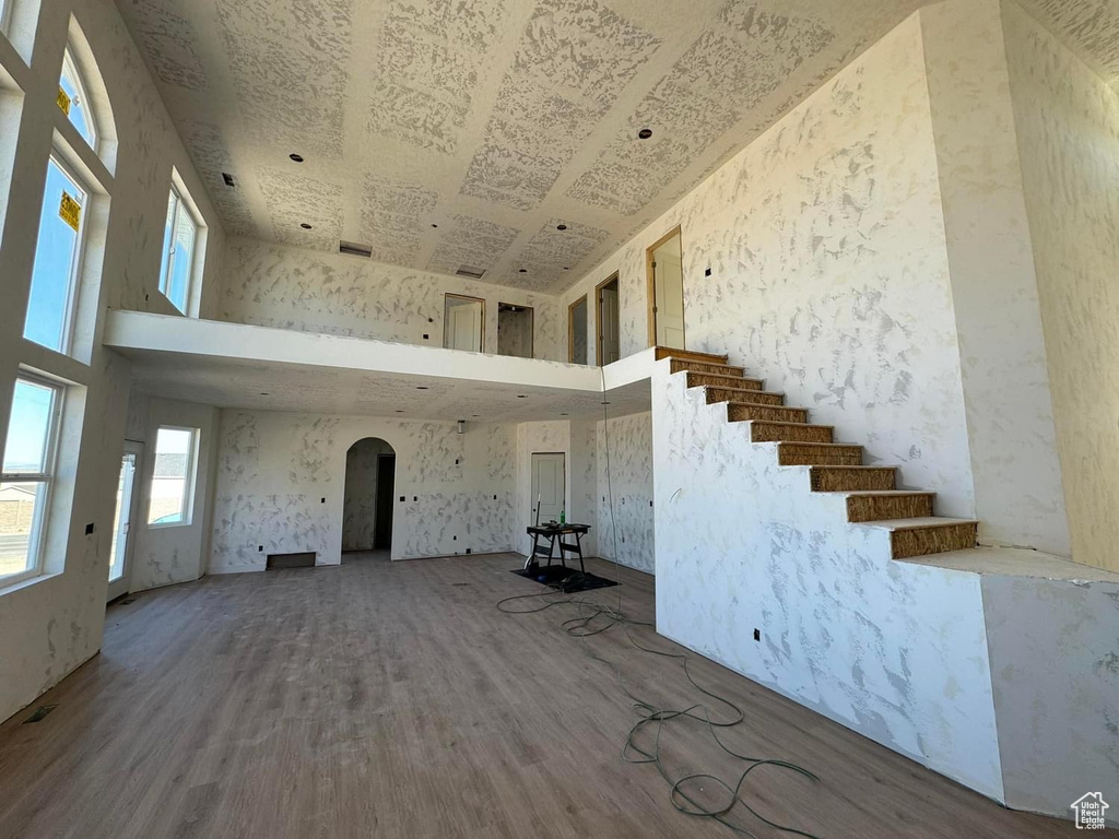 Unfurnished living room featuring hardwood / wood-style floors and a towering ceiling