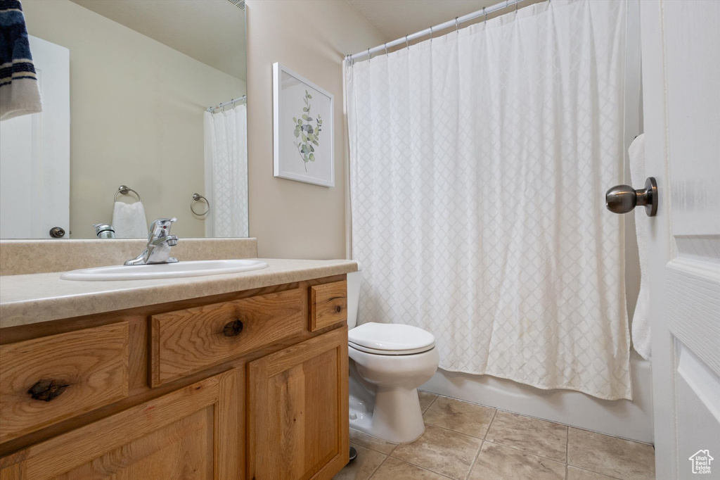 Full bathroom featuring toilet, tile flooring, large vanity, and shower / tub combo