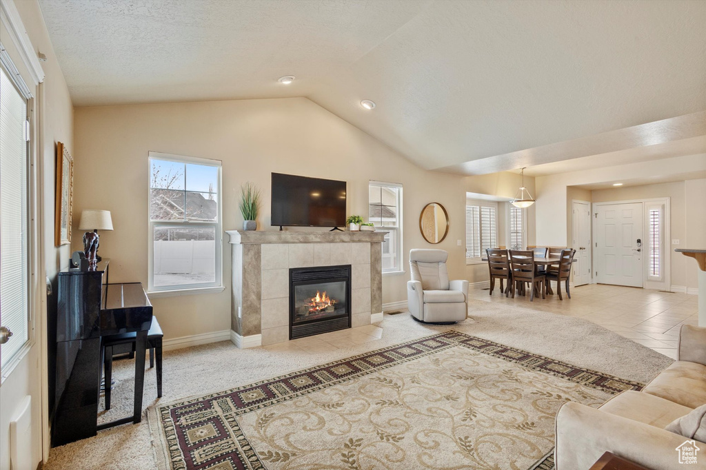 Living room featuring a fireplace, light tile floors, and vaulted ceiling
