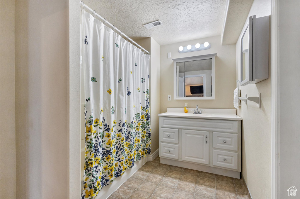 Bathroom with tile flooring, a textured ceiling, and vanity