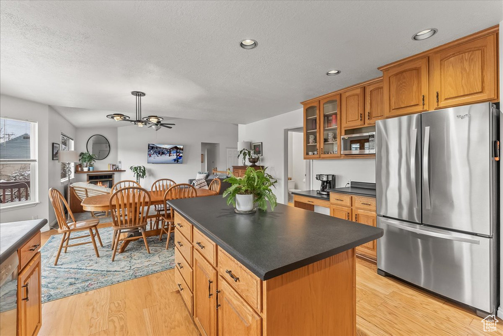 Kitchen featuring stainless steel appliances, ceiling fan, a center island, and light hardwood / wood-style flooring
