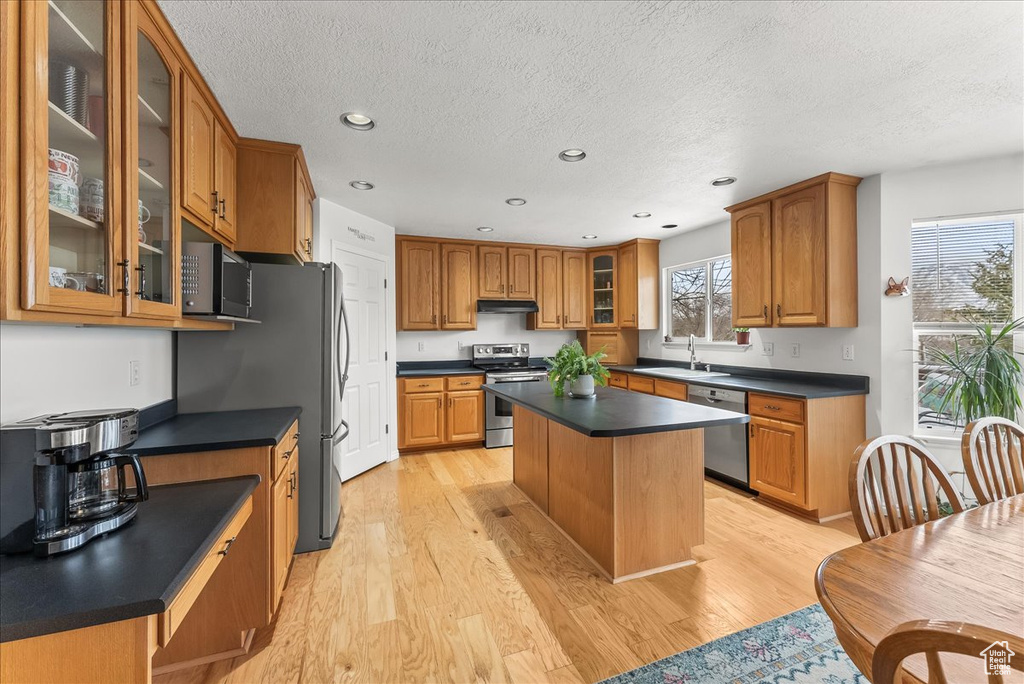 Kitchen featuring a kitchen island, stainless steel appliances, sink, and light hardwood / wood-style flooring