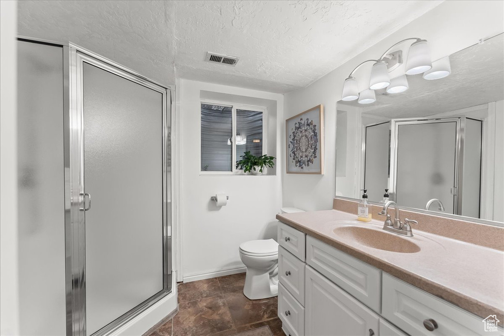 Bathroom featuring tile floors, a textured ceiling, toilet, oversized vanity, and an enclosed shower