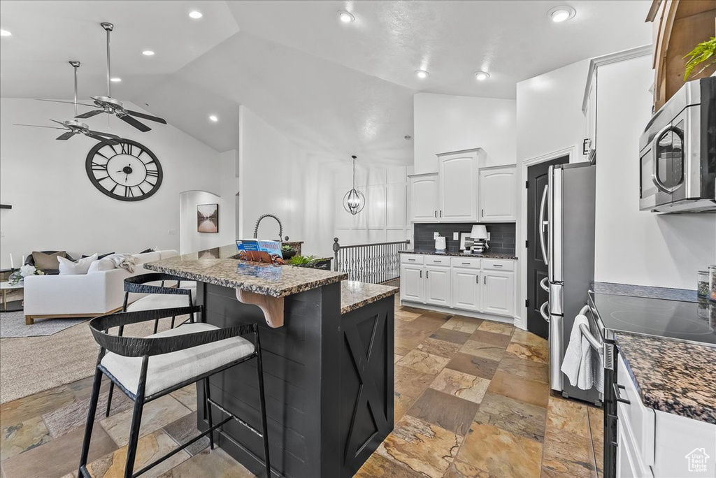 Kitchen featuring ceiling fan, tile floors, backsplash, white cabinetry, and stainless steel appliances