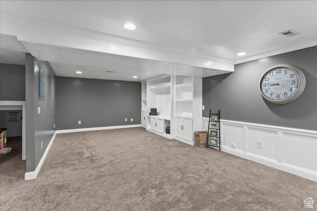 Basement featuring a textured ceiling, dark carpet, and crown molding