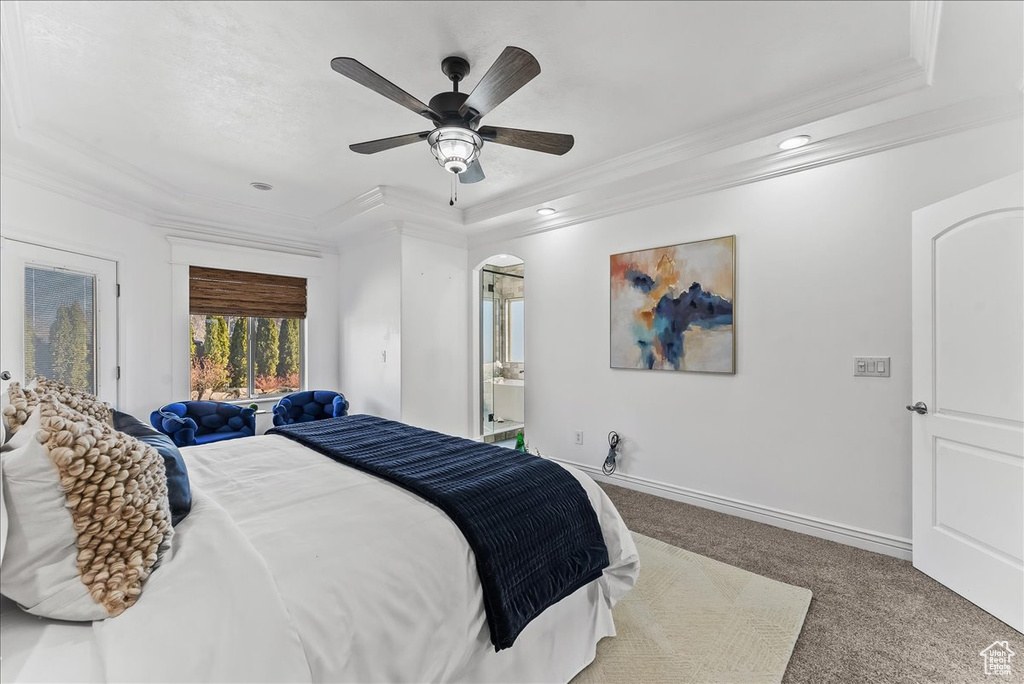 Carpeted bedroom featuring a raised ceiling, ornamental molding, and ceiling fan
