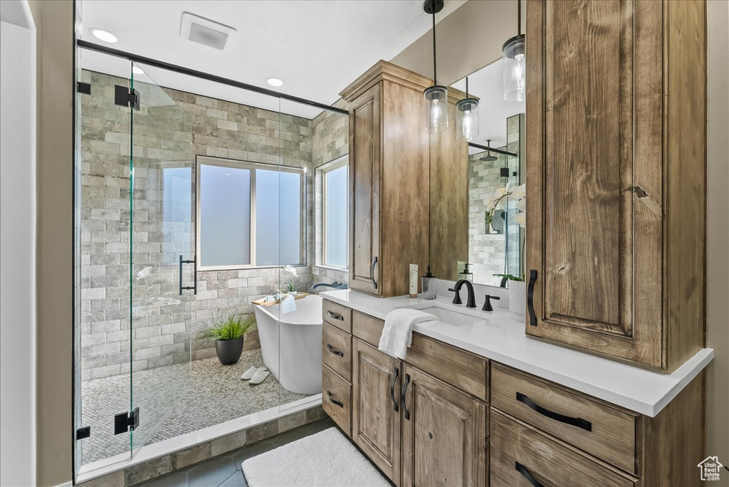 Bathroom with a shower with shower door, tile floors, and vanity