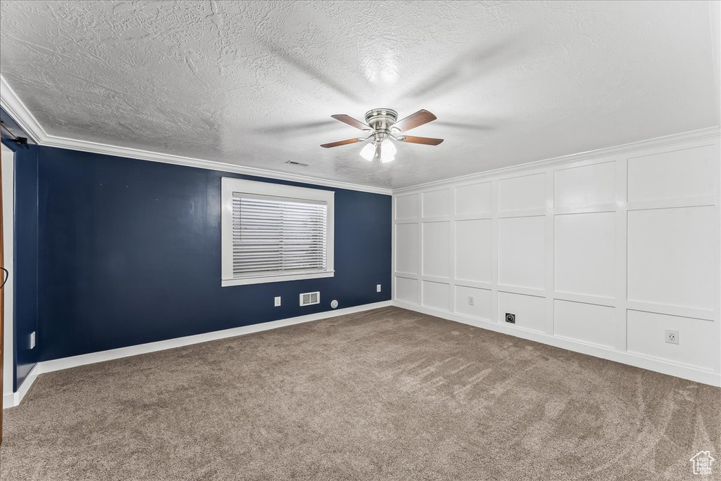 Unfurnished room with dark carpet, crown molding, a textured ceiling, and ceiling fan