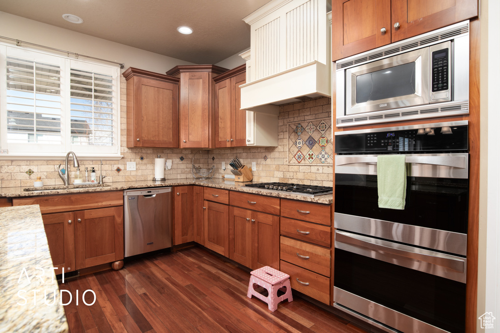 Kitchen with appliances with stainless steel finishes, tasteful backsplash, sink, and dark hardwood / wood-style floors