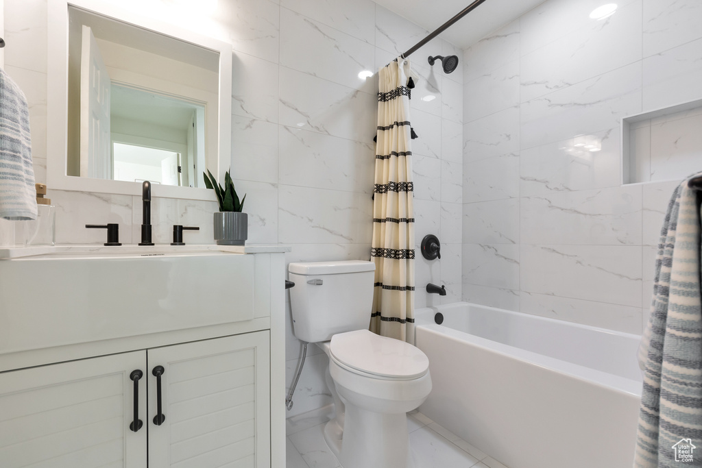Full bathroom with vanity, tile walls, shower / tub combo, toilet, and tile floors