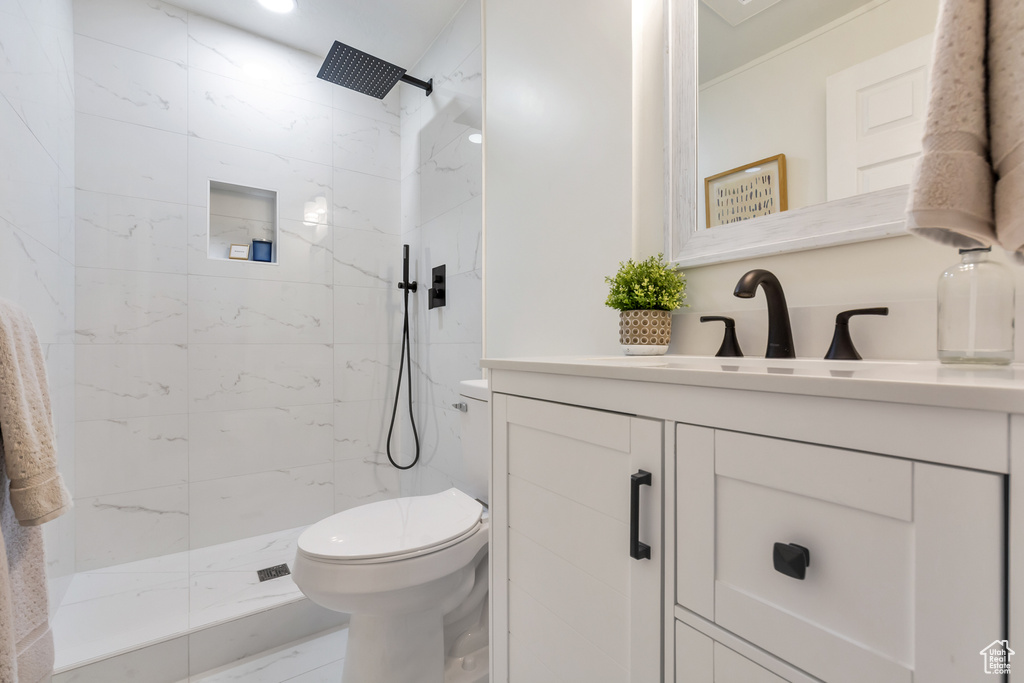 Bathroom with tiled shower, ornamental molding, toilet, and vanity with extensive cabinet space