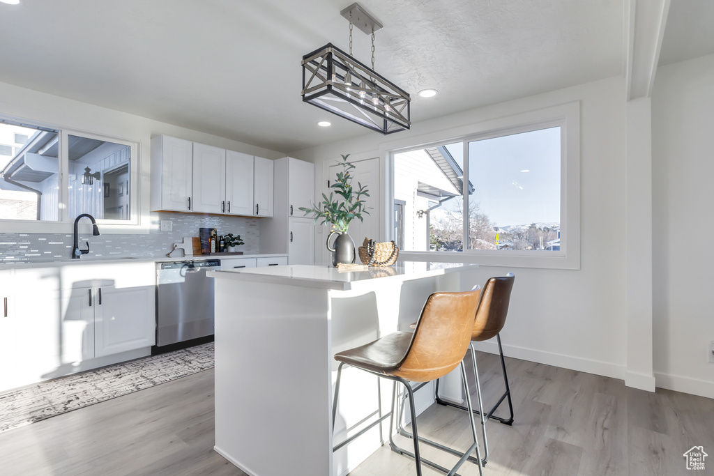 Kitchen featuring white cabinets, a kitchen island, light hardwood / wood-style floors, and a breakfast bar area