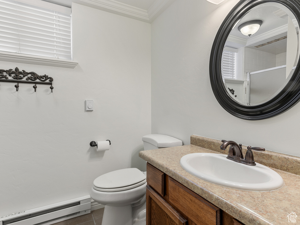 Bathroom with vanity with extensive cabinet space, toilet, baseboard heating, tile floors, and crown molding