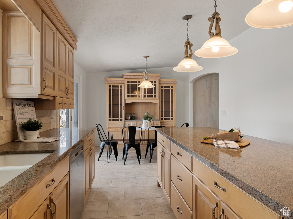 Kitchen featuring lofted ceiling, backsplash, light tile floors, dishwasher, and hanging light fixtures