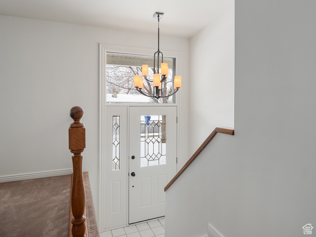 Foyer with an inviting chandelier and light colored carpet