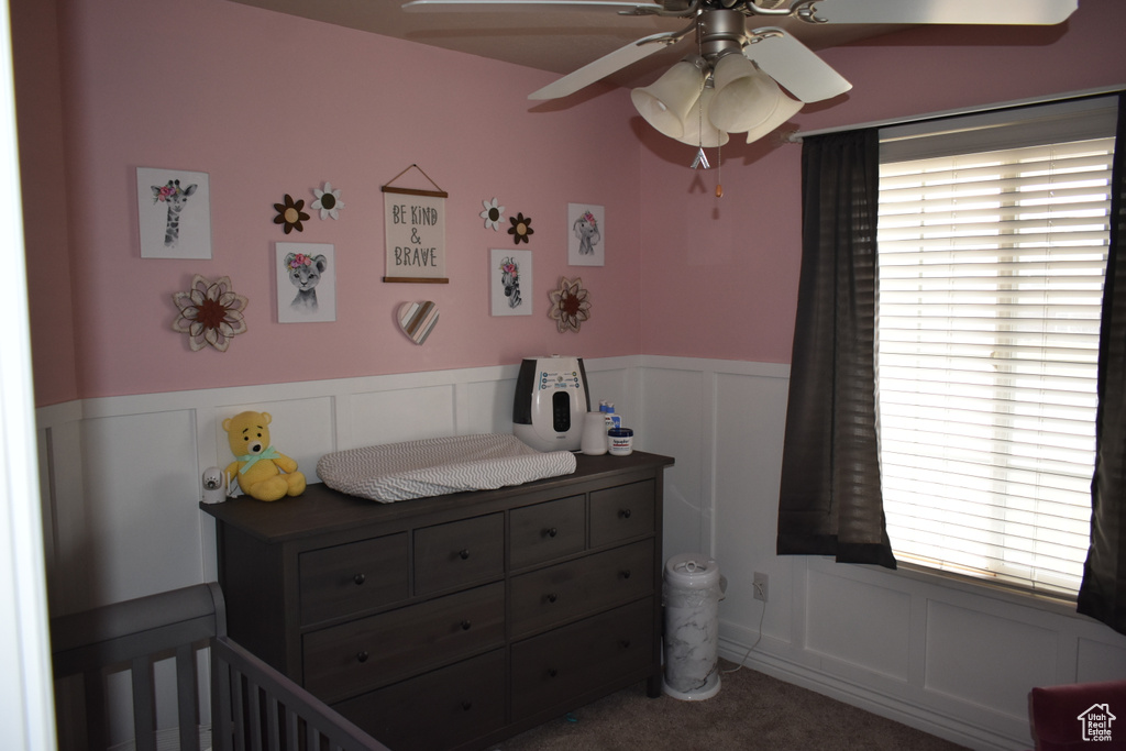 Bedroom featuring a crib, dark carpet, and ceiling fan