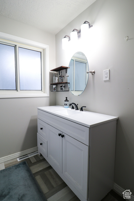 Bathroom with oversized vanity, hardwood / wood-style flooring, and a textured ceiling