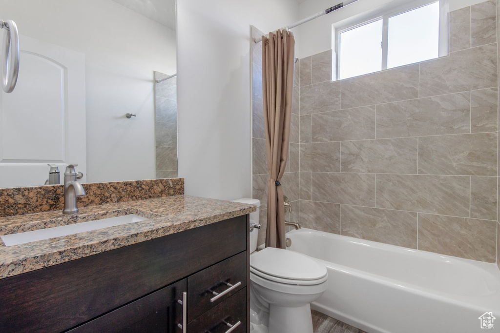 Full bathroom featuring shower / bathtub combination with curtain, toilet, and large vanity