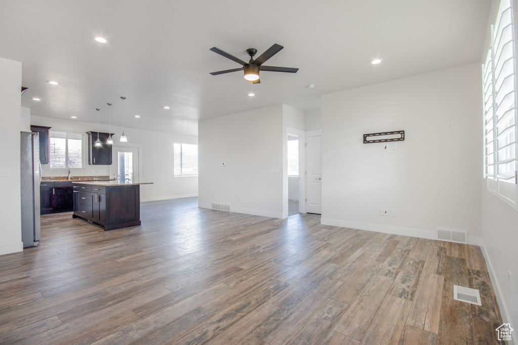 Unfurnished living room featuring ceiling fan and hardwood / wood-style floors