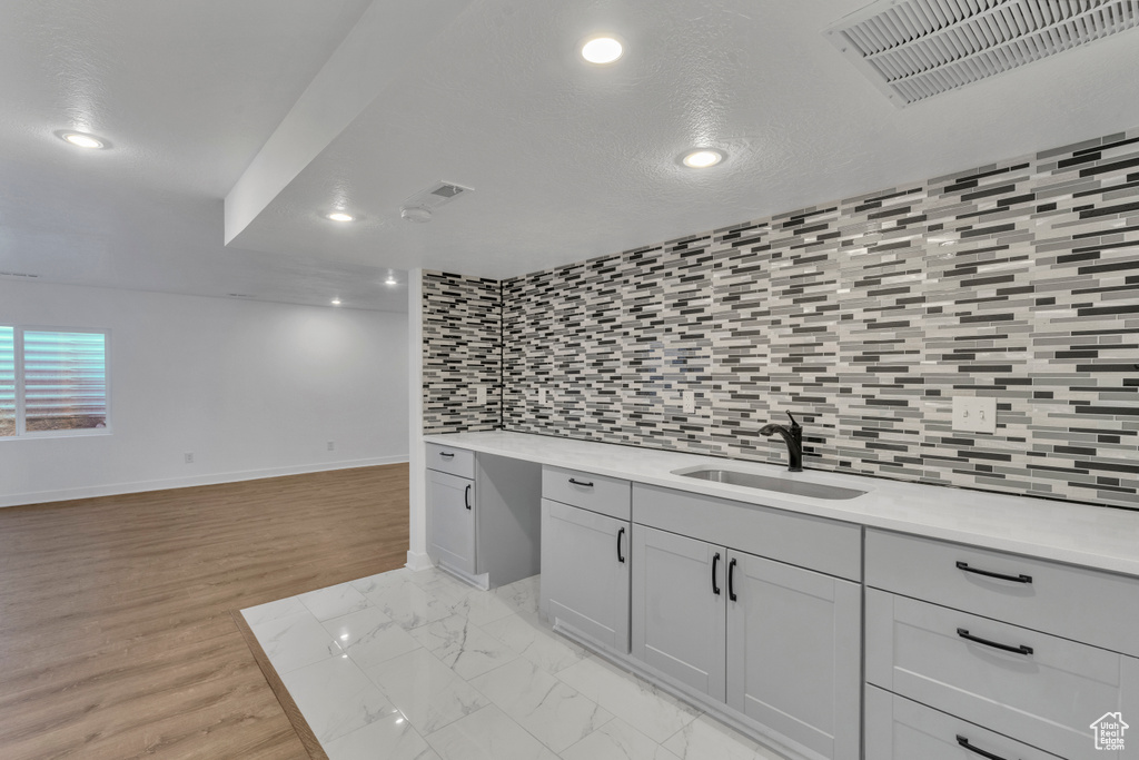 Kitchen with sink, light hardwood / wood-style floors, and tasteful backsplash