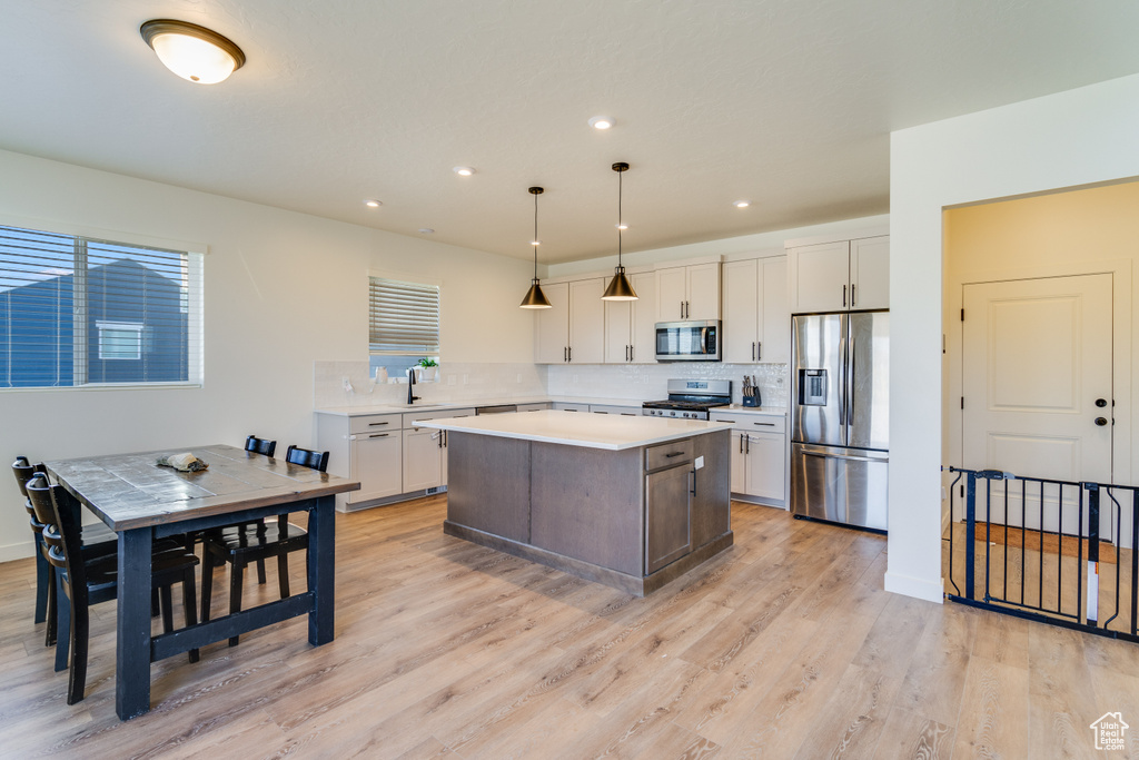 Kitchen featuring white cabinets, appliances with stainless steel finishes, pendant lighting, and a center island