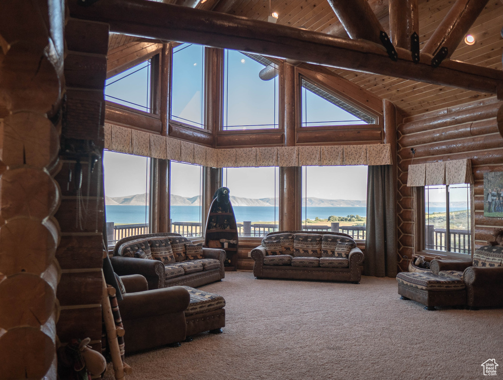 Carpeted living room featuring a water view, log walls, wooden ceiling, beam ceiling, and high vaulted ceiling
