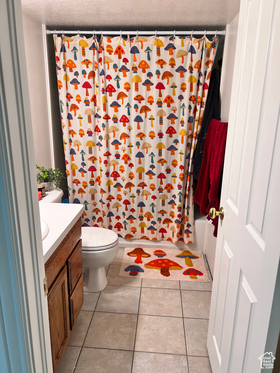 Full bathroom featuring a textured ceiling, shower / tub combo with curtain, tile floors, vanity, and toilet