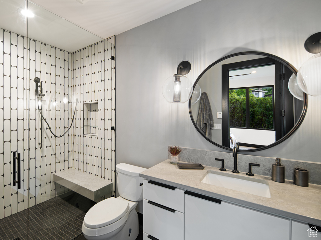 Bathroom with tiled shower, toilet, and vanity with extensive cabinet space