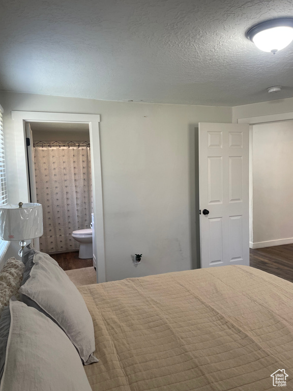 Bedroom featuring ensuite bathroom, dark hardwood / wood-style flooring, and a textured ceiling