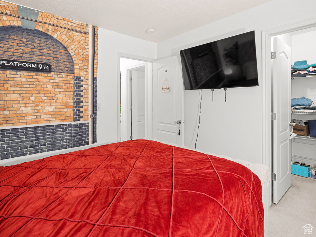 Carpeted bedroom featuring brick wall and a closet