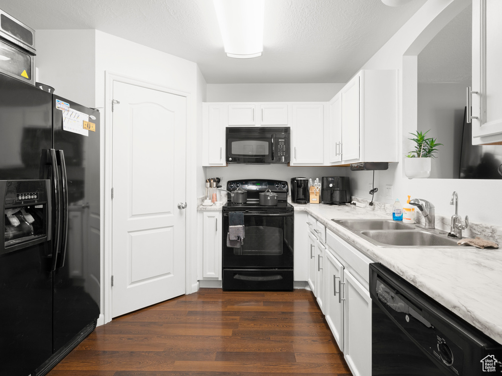 Kitchen featuring black appliances, dark hardwood / wood-style floors, white cabinetry, and sink