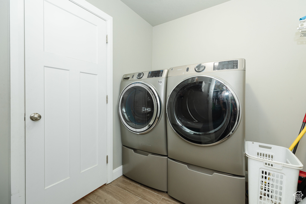 Laundry room featuring light wood-type flooring and washing machine and clothes dryer