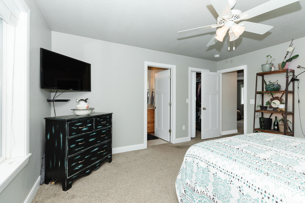 Bedroom with light colored carpet, ceiling fan, a closet, and ensuite bath