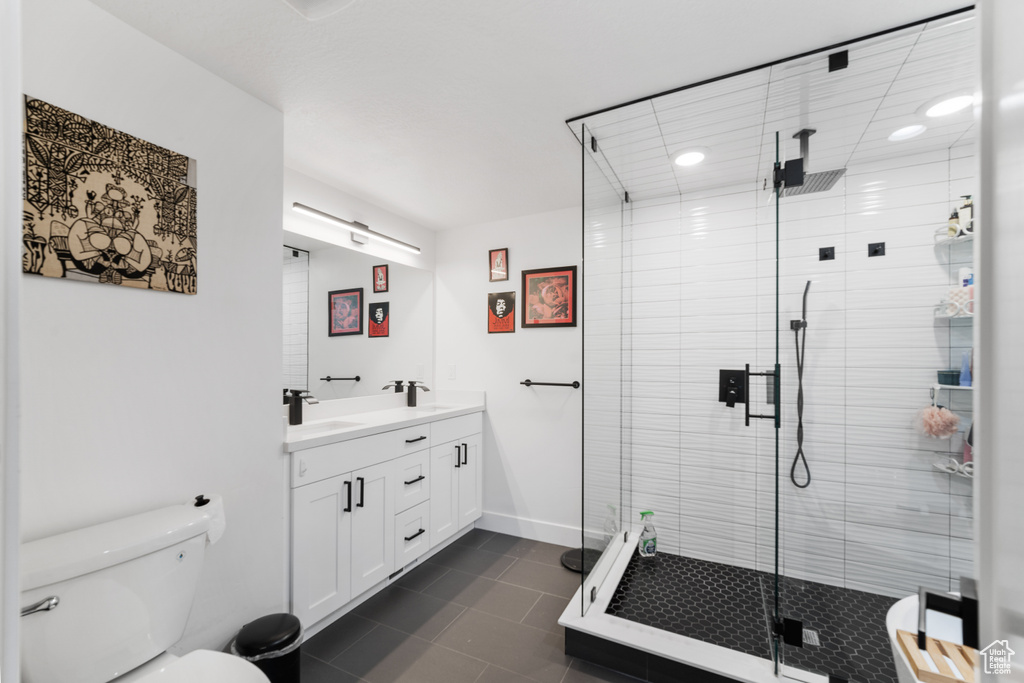 Bathroom with a shower with shower door, tile floors, toilet, and vanity