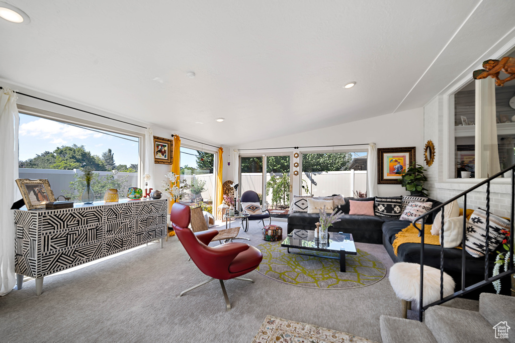 Carpeted living room featuring vaulted ceiling and a healthy amount of sunlight