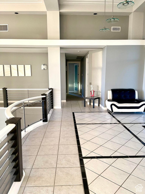 Hallway featuring light tile floors and a high ceiling