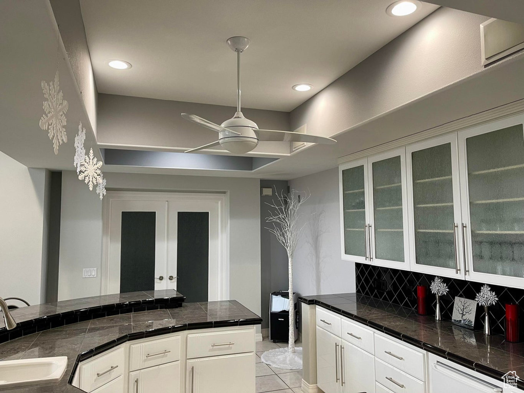 Kitchen featuring french doors, hanging light fixtures, ceiling fan, sink, and white cabinetry